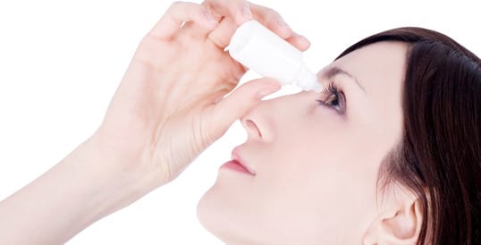 Woman using eye drops to combat winter dry eyes